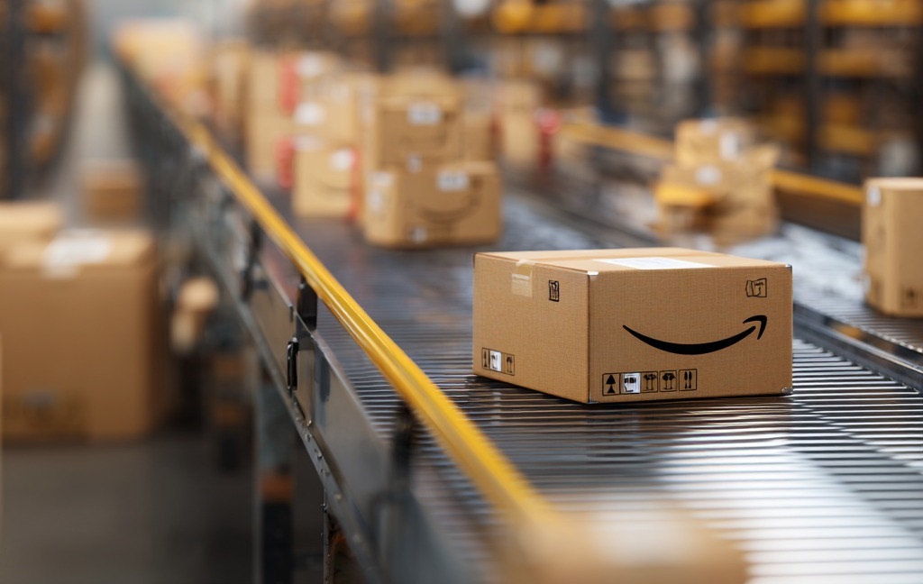 Amazon package on a conveyor belt in a fulfillment center, surrounded by other boxes in motion