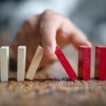 Hand preventing a row of domino blocks from falling