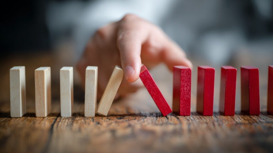 Hand preventing a row of domino blocks from falling